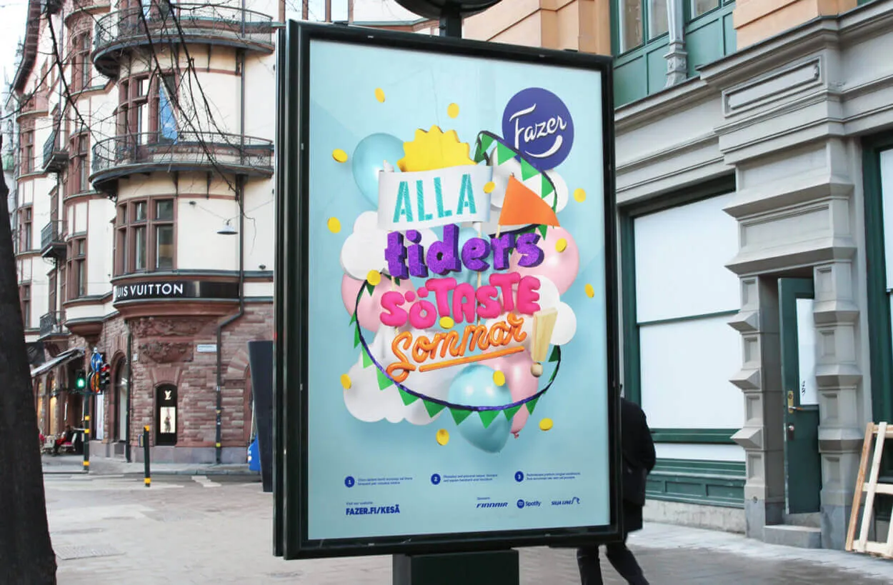 A colorful advertisement poster in a city street, featuring the Fazer logo and Swedish text 'ALLA tiders SÖTASTE Sommar' in a playful 3D-style font. The design includes balloons, confetti, and summer-themed elements on a pastel blue background. The ad is encased in a glass display with a European-style building and a Louis Vuitton store in the background.